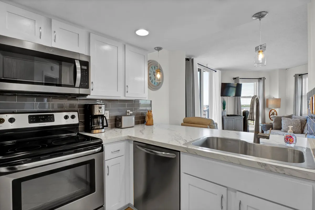 A spacious, modern kitchen with a generous marble countertop, sleek stainless steel appliances, an island for prep or casual meals, and a window offering natural light. The setup is ideal for both entertaining and everyday cooking.