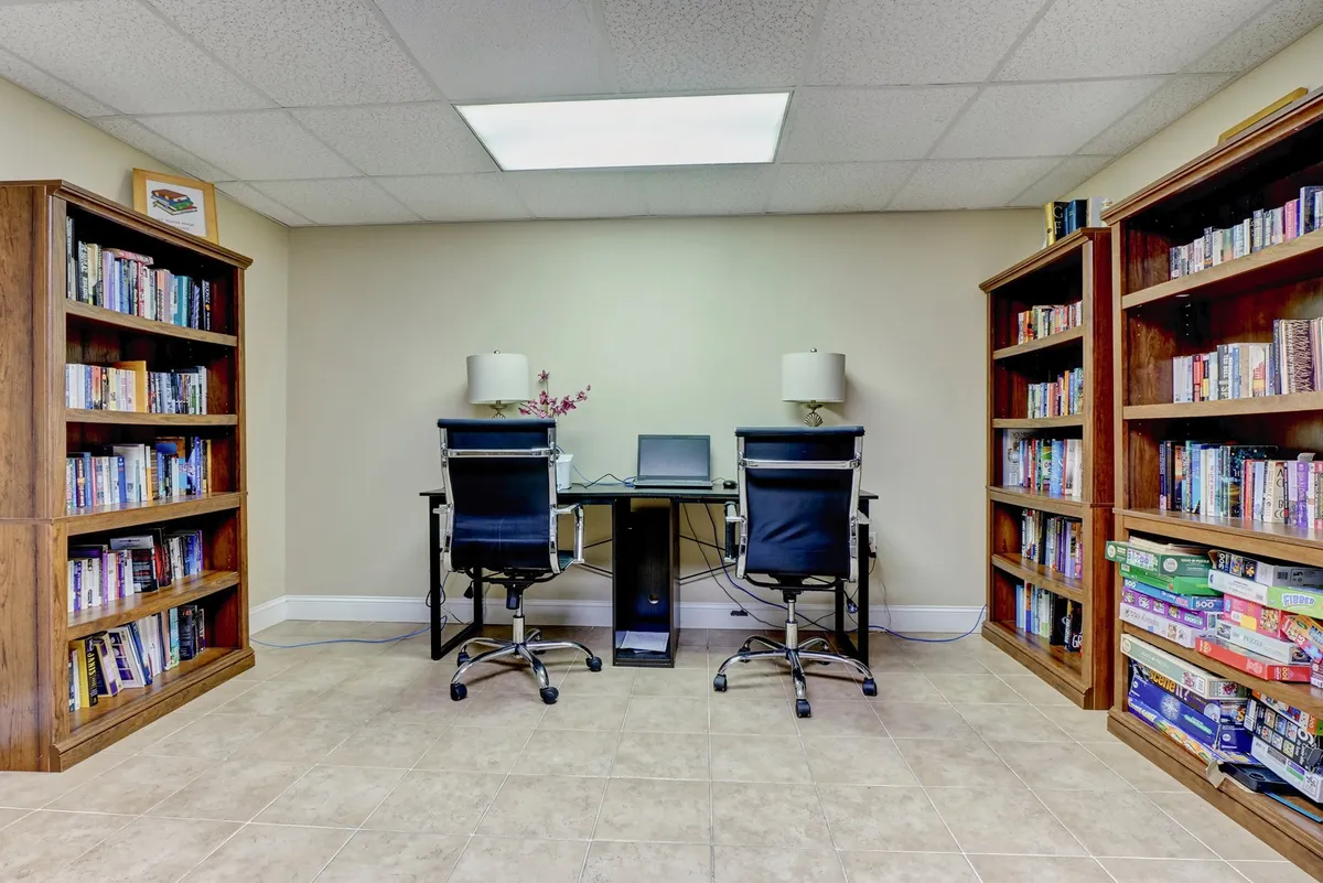 An interior space featuring bookshelves, desks, computers, and lamps, designed for quiet work and reading. It gives off a focused and serene vibe, ideal for business or study sessions.